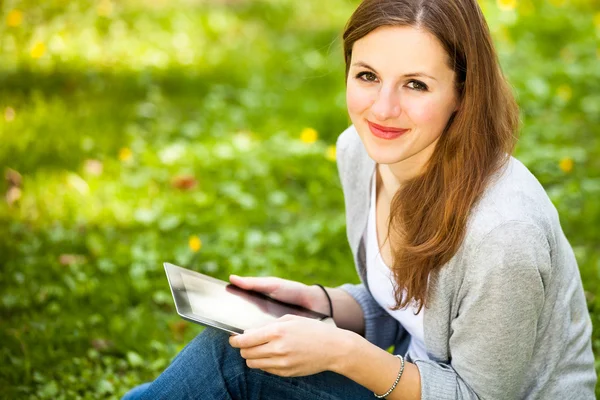 Jovem mulher usando seu computador tablet enquanto relaxa ao ar livre — Fotografia de Stock