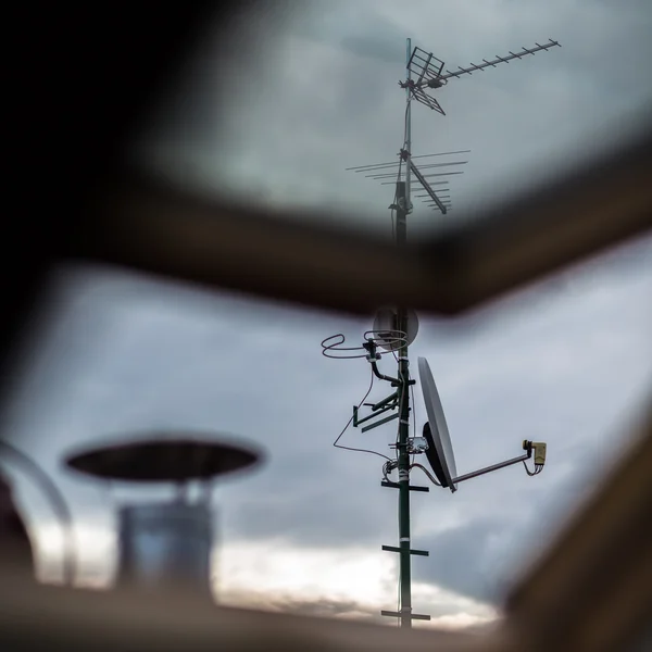 Antenas y una antena parabólica en un techo — Foto de Stock