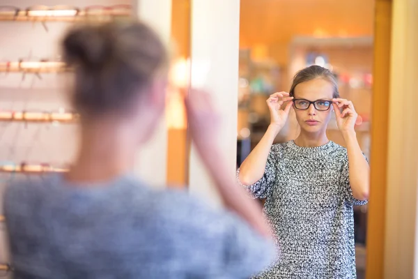 Mujer bonita y joven eligiendo nuevos marcos de gafas —  Fotos de Stock