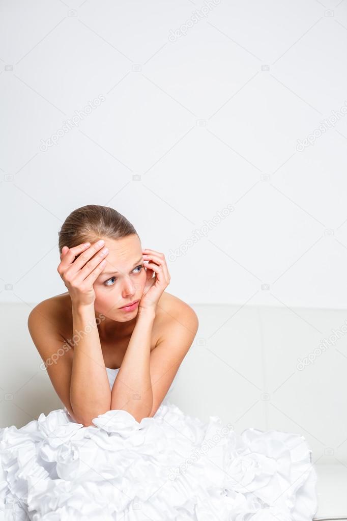 Sad bride crying sitting on a sofa, smitten, pondering