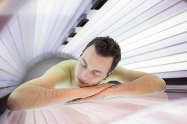 Yakışıklı delikanlı bir bronzlaşma oturum sırasında rahatlatıcı