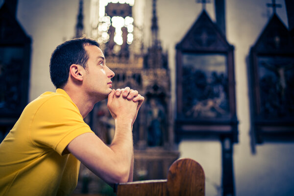 Handsome young man praying in a church