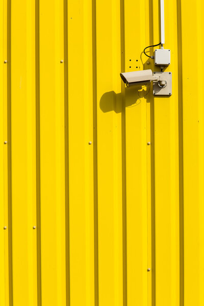 Security camera on a yellow wall