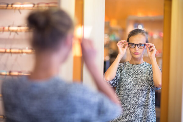 Pretty, young woman choosing new glasses frames