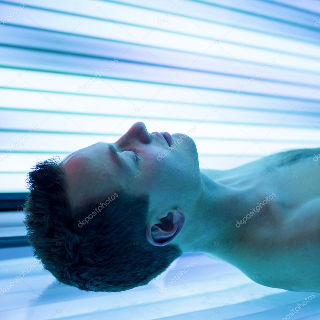 Handsome young man relaxing during a tanning session