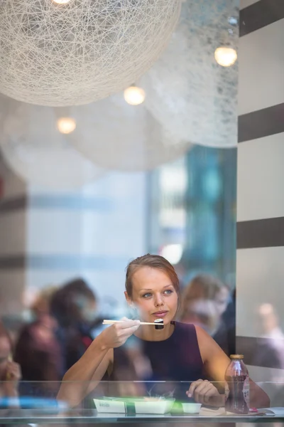 Jolie, jeune femme mangeant des sushis dans un restaurant — Photo