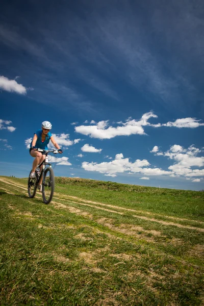 Bonito, jovem motociclista ao ar livre em sua bicicleta de montanha (movimento — Fotografia de Stock