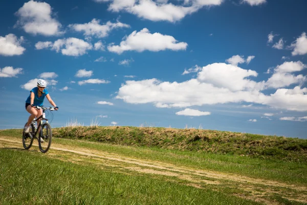 Pretty, young female biker outdoors on her mountain bike (motion — Stock Photo, Image