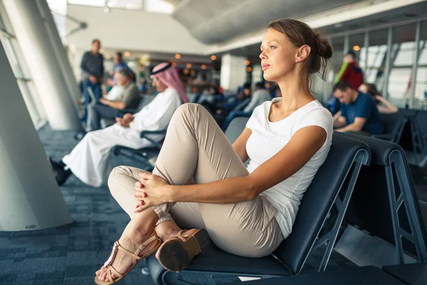 Guapa, joven mujer esperando en un área de puerta de un aeropuerto moderno f — Foto de Stock