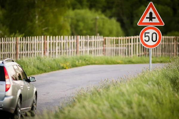 Carro em estrada de campo com velocidade limitada e sinal de encruzilhada — Fotografia de Stock