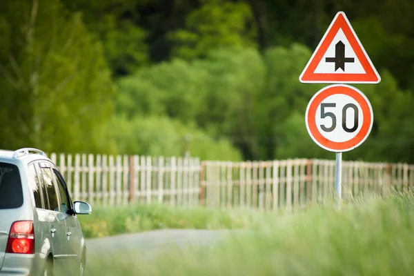 Αυτοκίνητο σε έναν επαρχιακό δρόμο με περιορισμένη ταχύτητα και σταυροδρόμι σημάδι — Φωτογραφία Αρχείου