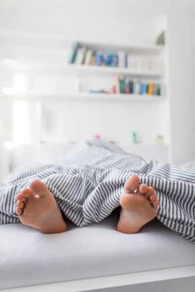 Pés de uma pessoa dormindo na cama em brilhante — Fotografia de Stock