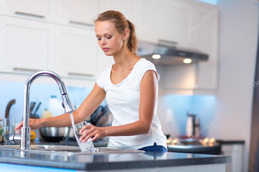 Pretty, young woman in her modern, clean and bright kitchen, pou