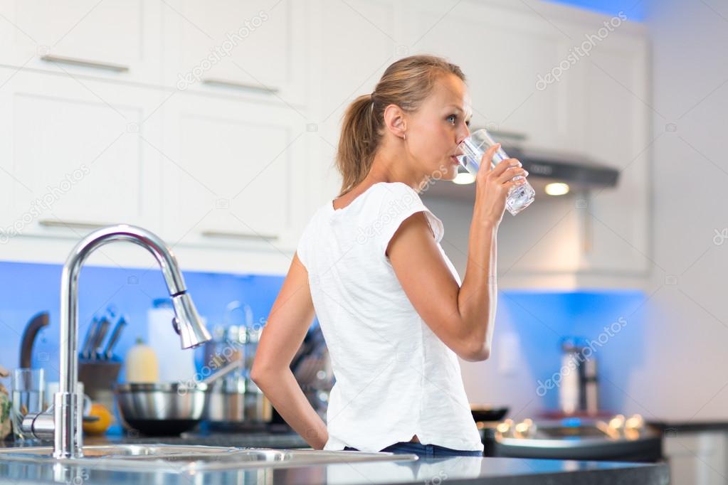 Pretty, young woman in her modern, clean and bright kitchen, pou
