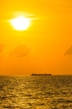Kargo gemisi gün batımında yola çıkıyor.