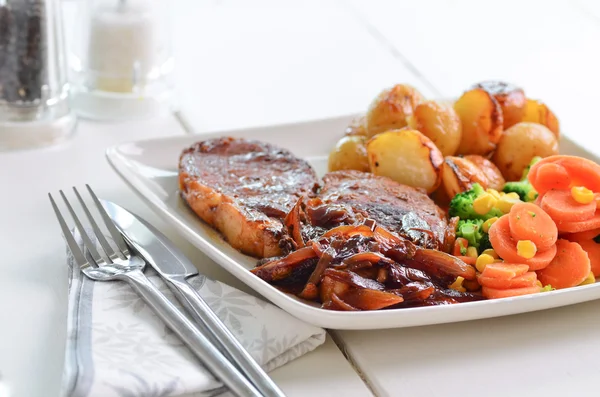 Schweinekotelett Sonntag Mittagessen mit Zwiebelsoße. lizenzfreie Stockfotos