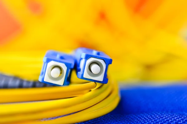 Conectores de fibra óptica de perto em um fundo colorido . Imagem De Stock