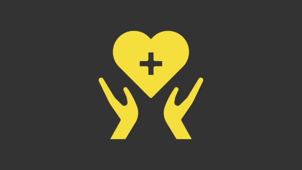 灰色の背景に孤立した十字アイコンを持つ黄色のハート。応急処置だ。ヘルスケア、医療、薬局の看板。4Kビデオモーショングラフィックアニメーション — ストック動画
