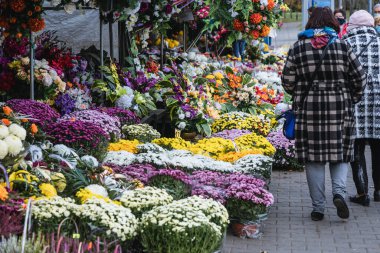 Warsaw, Poland - October 29, 2020: Women passes next to stand with flowers on Wolski Cemetery just before All Saints Day in Warsaw, capital of Poland clipart