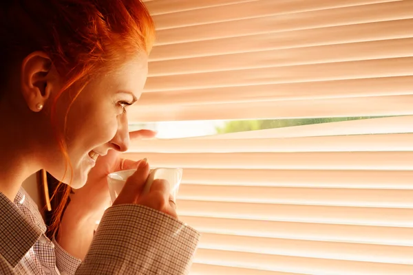 Vacker kvinna tidigt på morgonen med kopp kaffe på fönster — Stockfoto