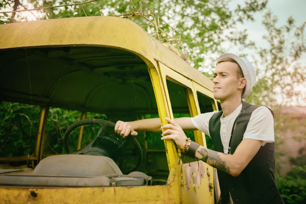 young man hipster tries to get old retro car bus