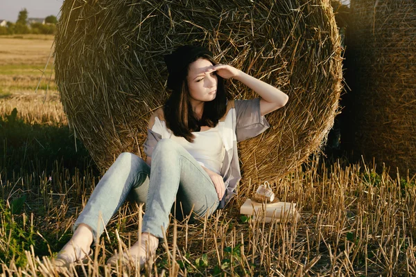 Hermosa chica hipster mira distancia contra la paca de heno en otoño — Foto de Stock