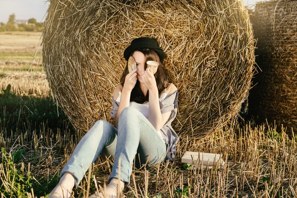 Meisje hipster dekt staartdeling gezicht tegen baal hooi — Stockfoto