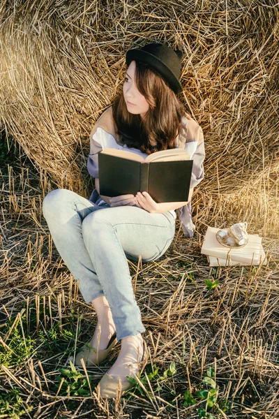 Girll hipster lee libro contra paca de heno en otoño — Foto de Stock