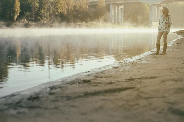 Lonely beautiful girl walks on river bank early in morning — Stock Photo, Image