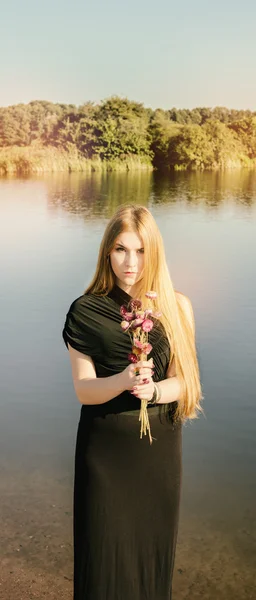 Chica gótica inusual con el pelo largo y rojo y flores secas cerca del lago — Foto de Stock