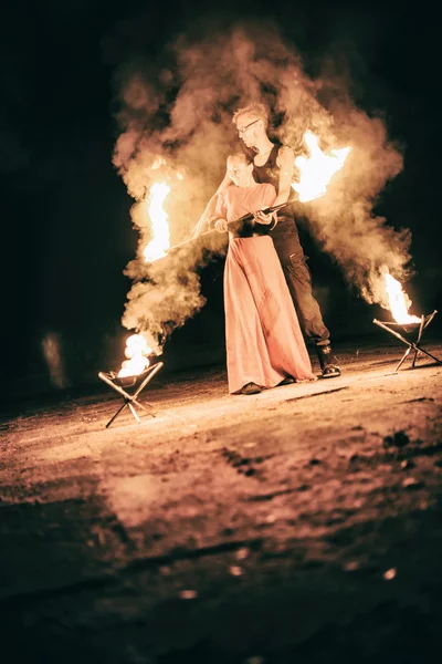 Активные девушки и мальчики выполняют трюки для огненного шоу ночью — стоковое фото