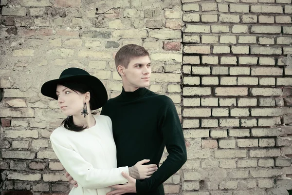 Unusual young couple love in spring with brick wall — Stock Photo, Image