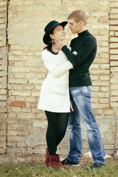 Unusual young couple love in spring with brick wall — Stock Photo, Image