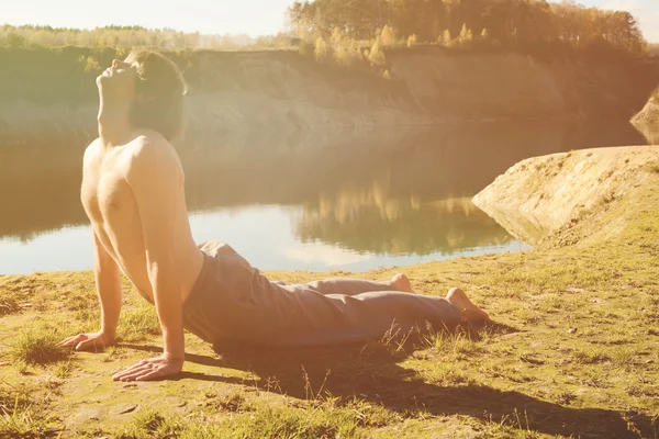 L'homme pratique asanas sur le yoga en harmonie avec la nature Images De Stock Libres De Droits