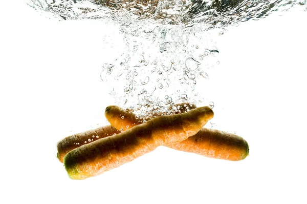 Frutas de cenoura caem profundamente sob a água — Fotografia de Stock