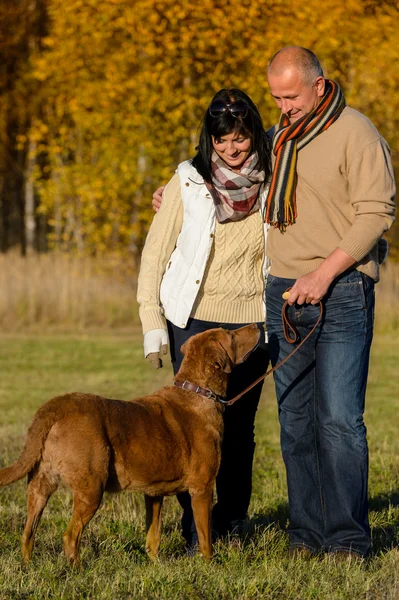 Casal com cão no ensolarado parque de outono — Fotografia de Stock