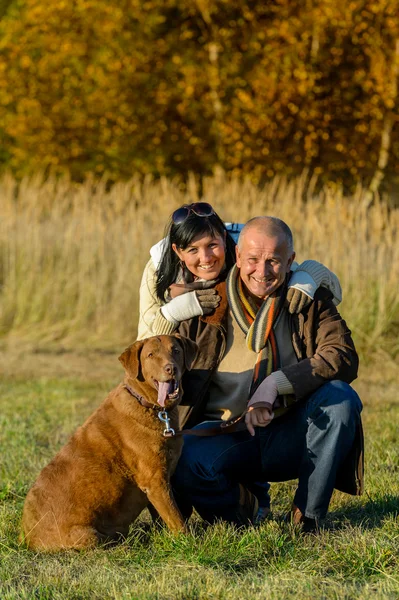 Fröhliches Paar mit Hund im Herbstpark Stockbild
