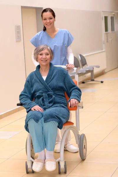 Krankenschwester schubst Seniorin im Rollstuhl lizenzfreie Stockfotos