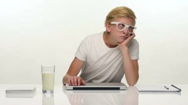Sıkılmış genç öğrenci dizüstü bilgisayar ile masasının önünde