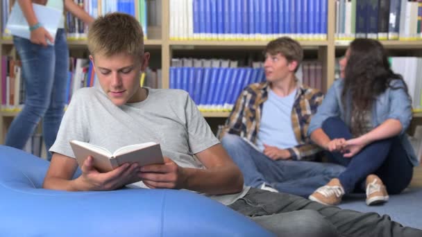 Étudiant garçon lecture sur haricot dans collège bibliothèque — Video