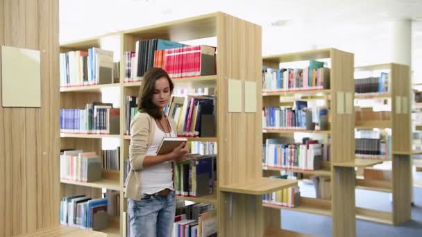 Student meisje pick-up een boek uit de bibliotheek planken — Stockvideo