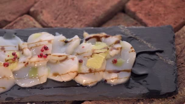 Närbild av pilgrimsmusslor med röd paprika på skiffer tallrik — Stockvideo