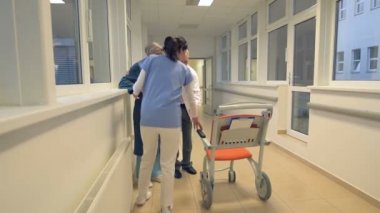 Tıbbi ekip hasta tekerlekli sandalyede oturmak için yardım