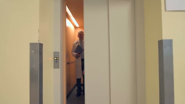 Medicinska teamet med patienten i rullstol går ur hissen — Stockvideo