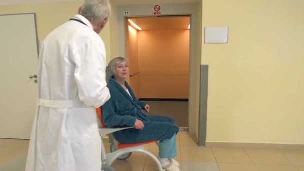 Sjuksköterska med patienten i rullstol kommer ut från sjukhuset lift — Stockvideo