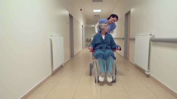 Senior im Rollstuhl mit Krankenschwester im Krankenhausflur — Stockvideo