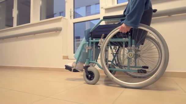 Disabled patient in wheelchair moving down hospital hallway — Stock Video