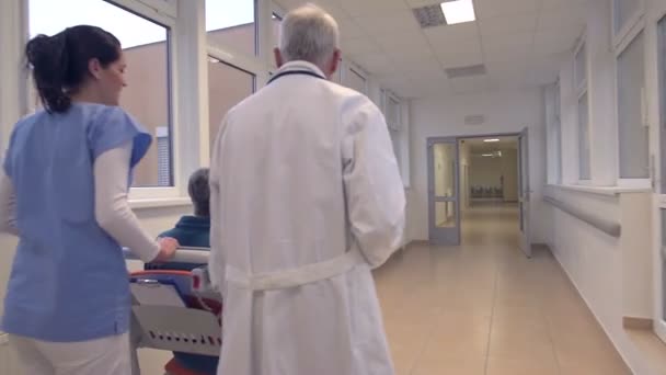 Sjuksköterska driver patienten i rullstol på sjukhus — Stockvideo