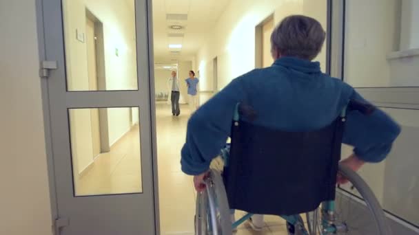 Senior in wheelchair passing medical team — Stock Video