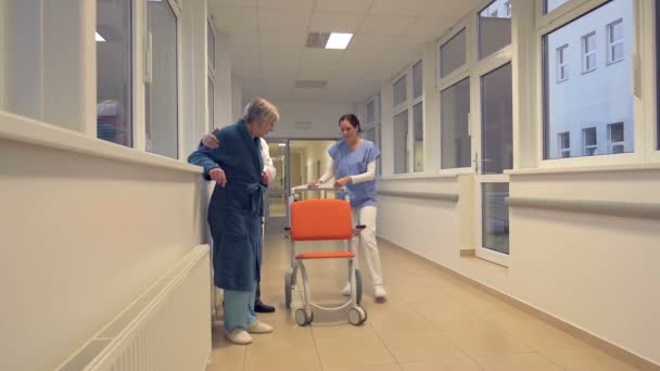 Equipe médica ajudando o paciente a se sentar em cadeira de rodas — Vídeo de Stock